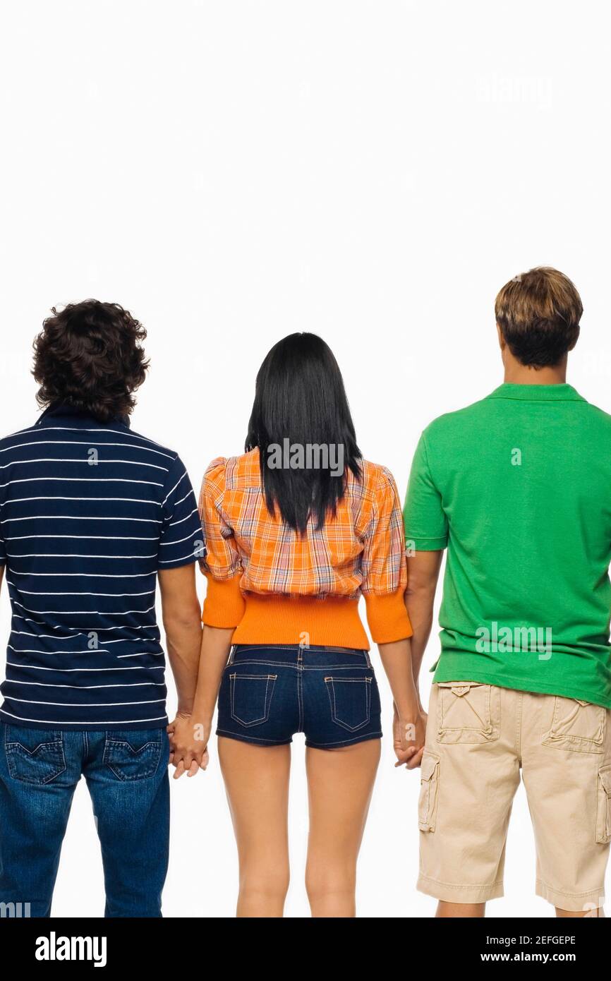 Rückansicht einer jungen Frau und zwei Männer stehen mit ihren Händchen Stockfoto