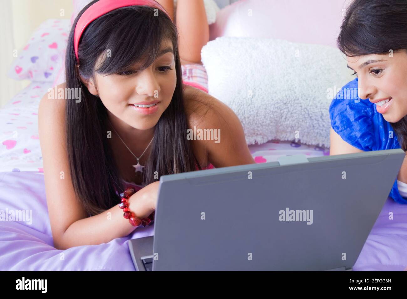 Teenager-Mädchen und eine junge Frau mit Blick auf einen Laptop und lächelnd Stockfoto
