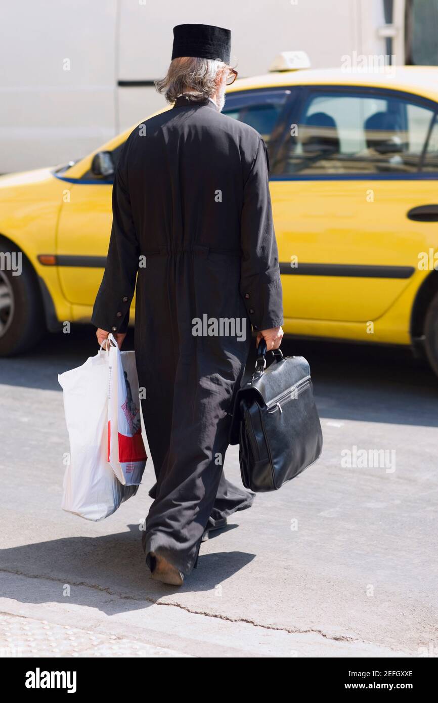 Rückansicht eines reifen Mannes, der Gepäck zu einem Taxi trägt, Athen, Griechenland Stockfoto