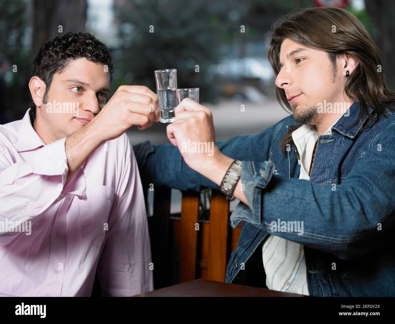 Zwei junge Männer toasten mit Schnapsgläsern aus Tequila Stockfoto