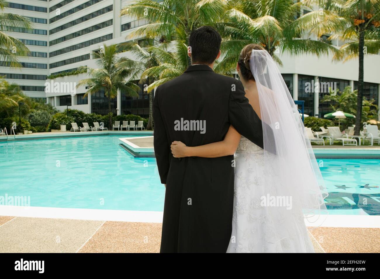 Rückansicht eines frisch vermählten Paares, das am Pool stand Stockfoto