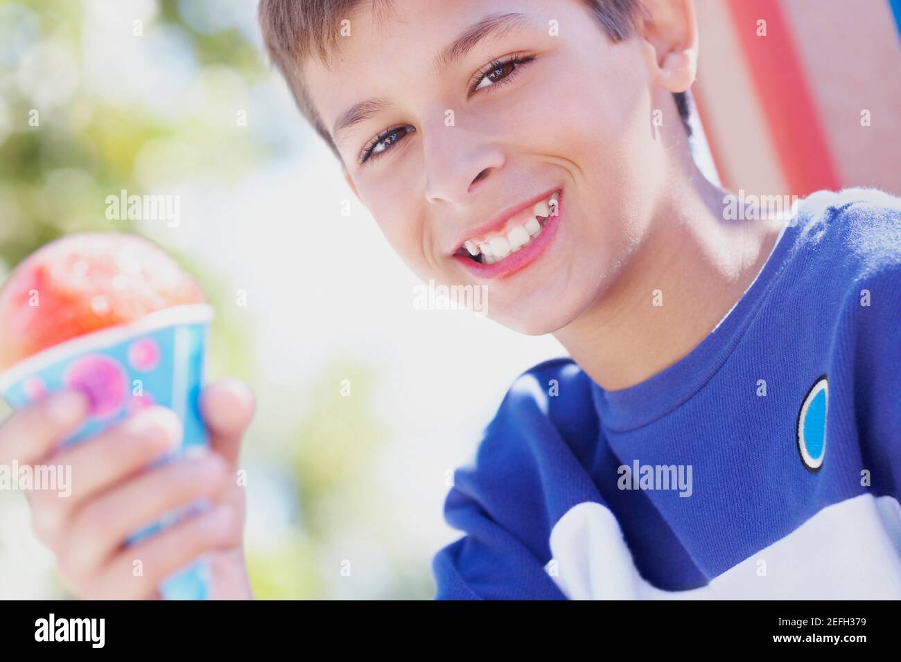 Porträt eines Jungen im Teenageralter, der lächelt und ein Eis hält Kegel Stockfoto