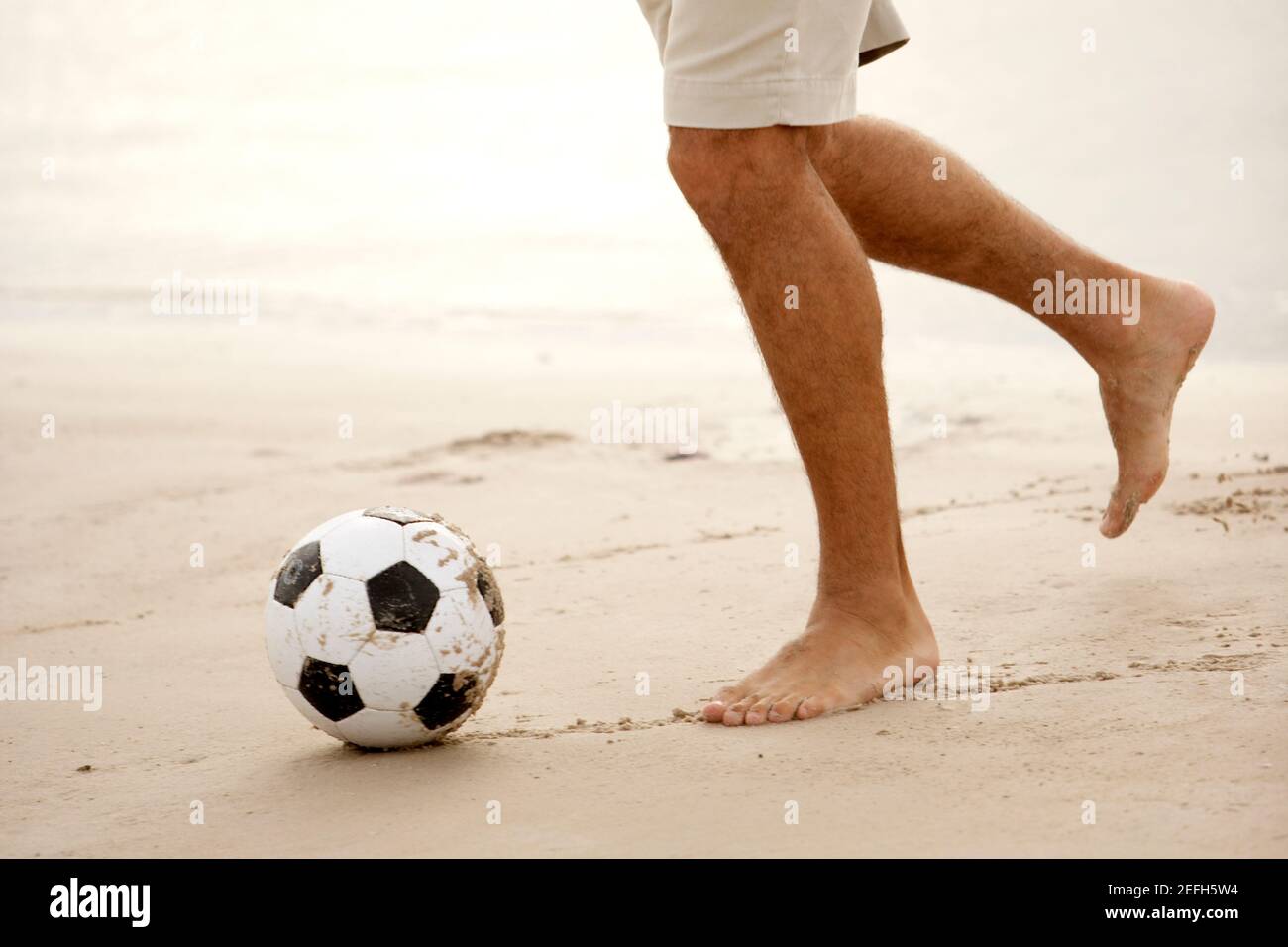Blick auf einen Mann mit mittlerem Erwachsenen, der Fußball spielt Am Strand Stockfoto