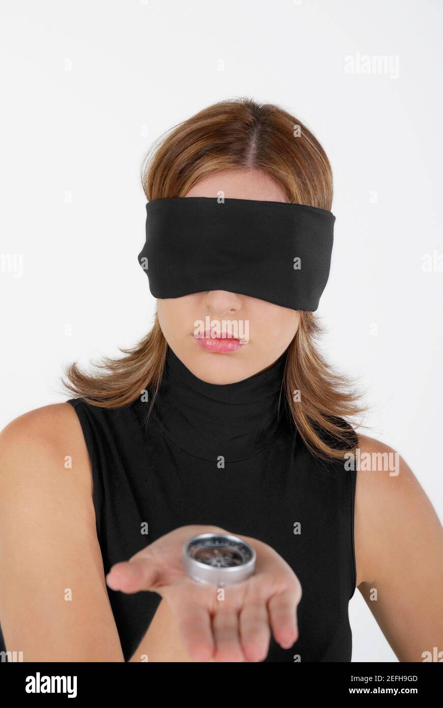 Nahaufnahme einer Geschäftsfrau, die mit ihren Augen einen Kompass zeigt Mit verbundenen Augen Stockfoto