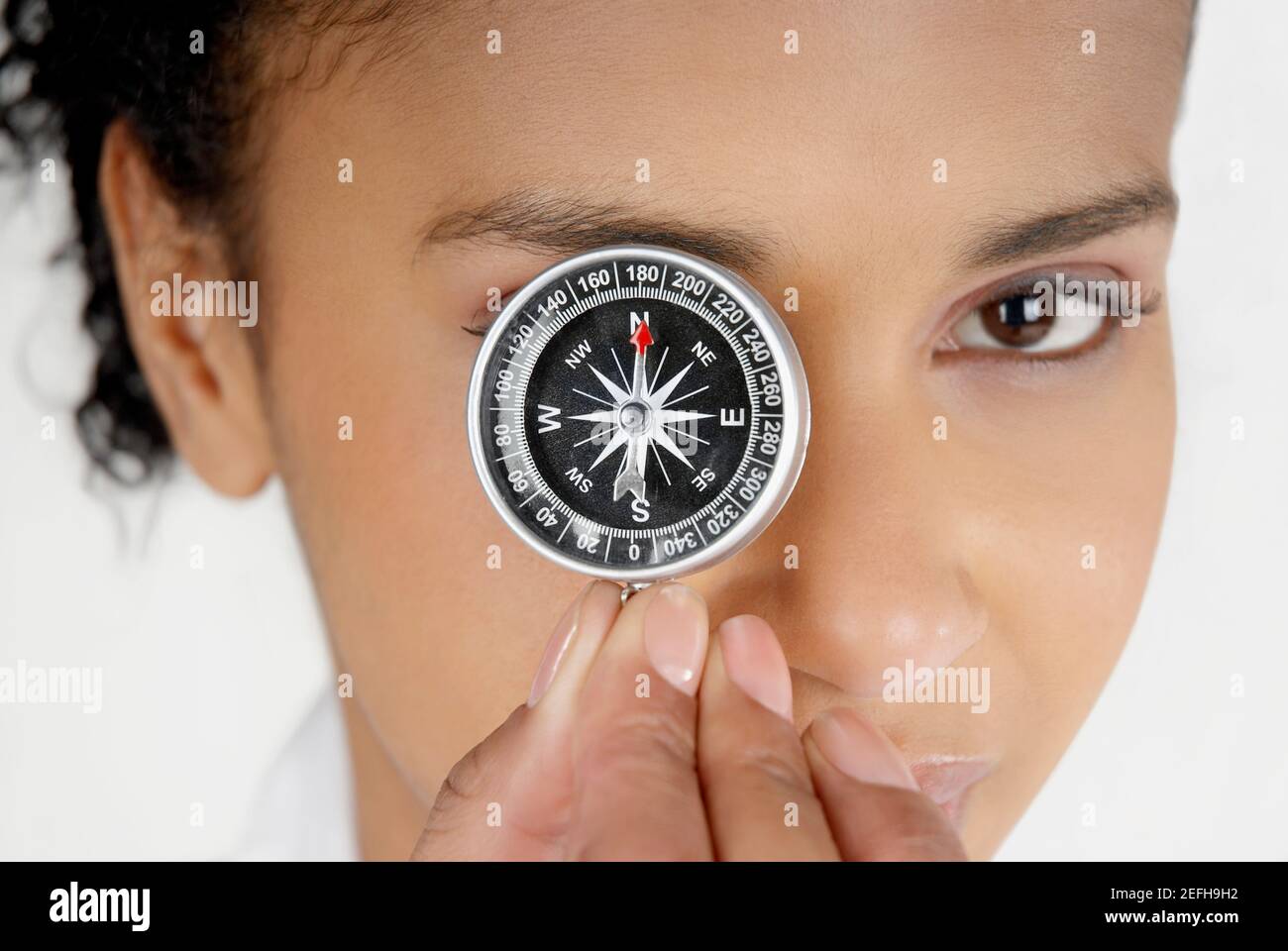 Porträt einer Geschäftsfrau, die ihr Auge mit einem Kompass bedeckt Stockfoto