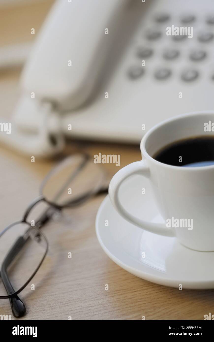 Nahaufnahme von Brillen und einer Teetasse vor Ein Telefon Stockfoto