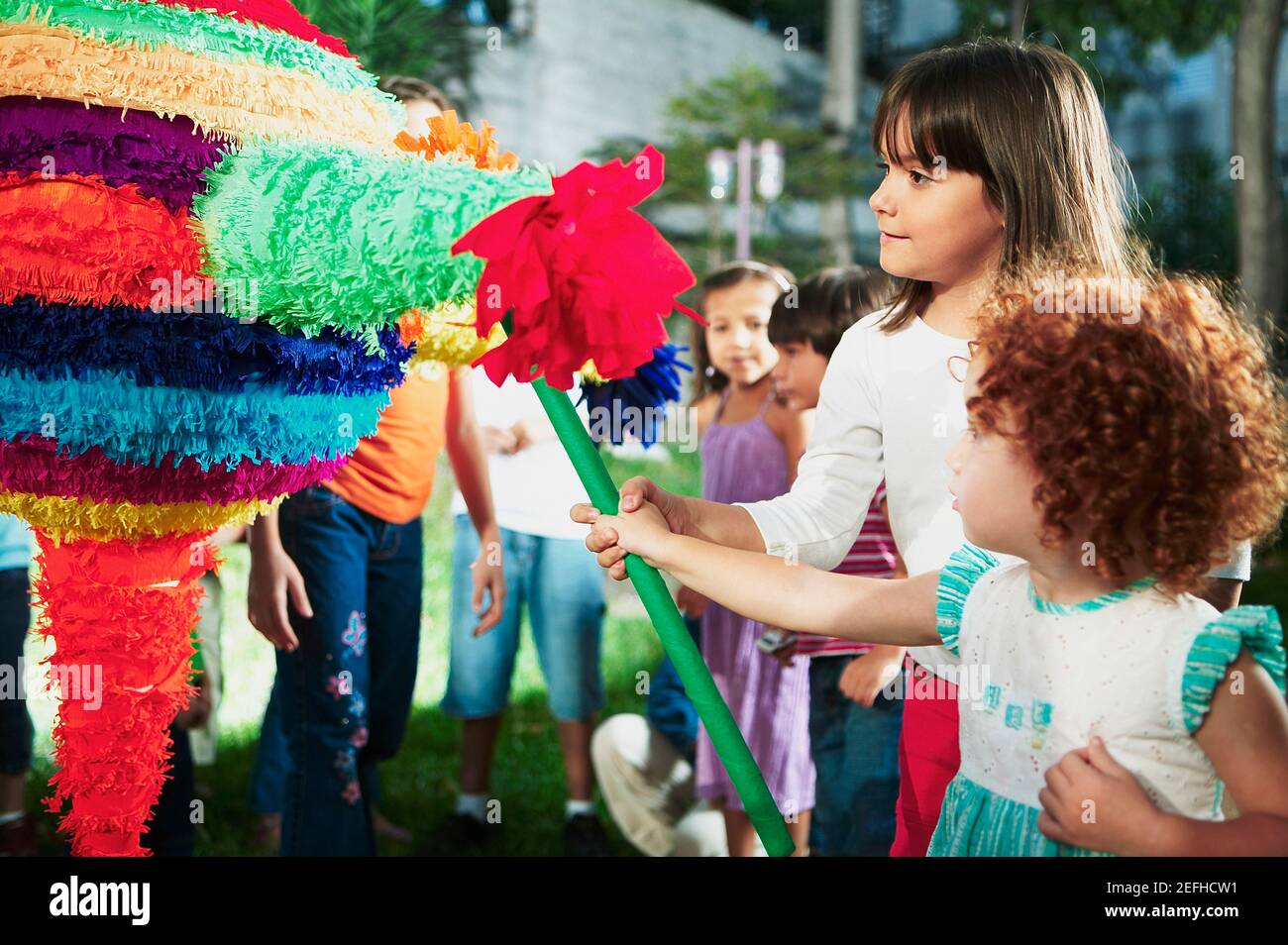 Close up von zwei Mädchen schlagen eine Pinata mit einem Stock Stockfoto