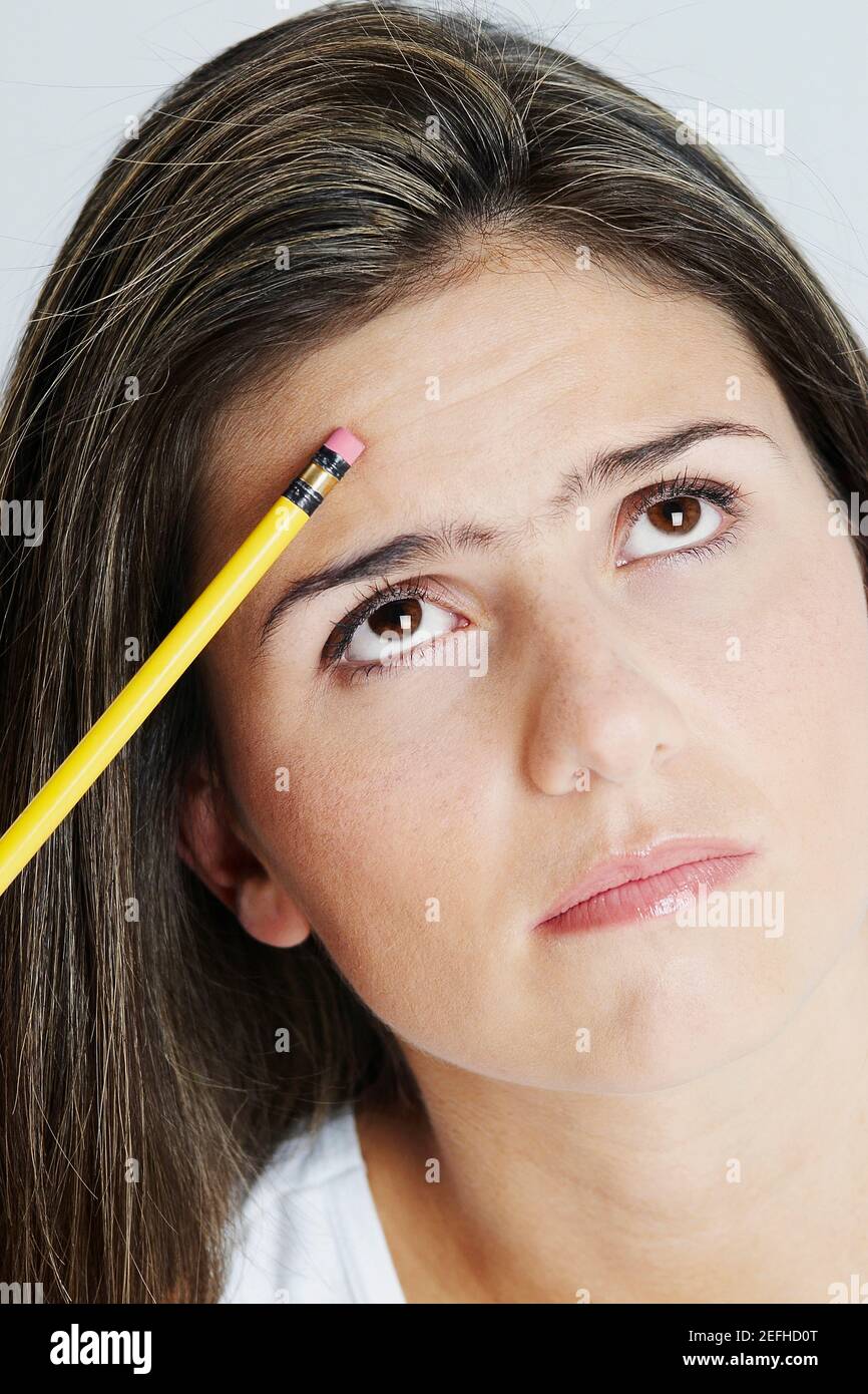 Nahaufnahme einer jungen Frau, die einen Bleistift hält und denkt Stockfoto