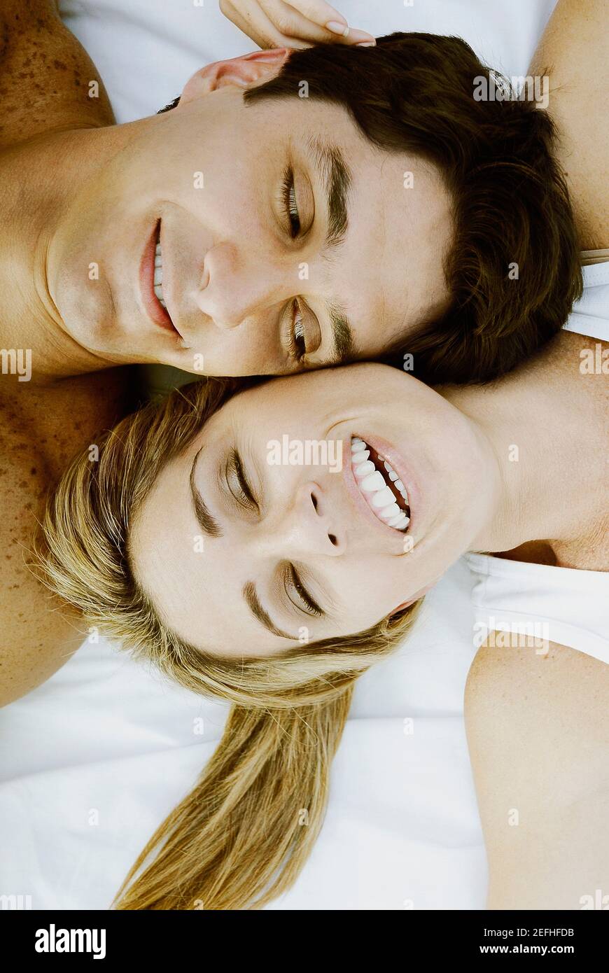 Blick auf ein Paar mittlerer Erwachsene, das auf dem Zimmer liegt Das Bett und lächelnd Stockfoto