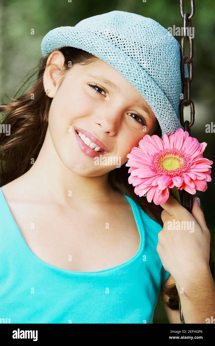 Porträt eines Mädchens lächelnd auf einer Kettenschaukel Fahrt Mit einer Blume Stockfoto