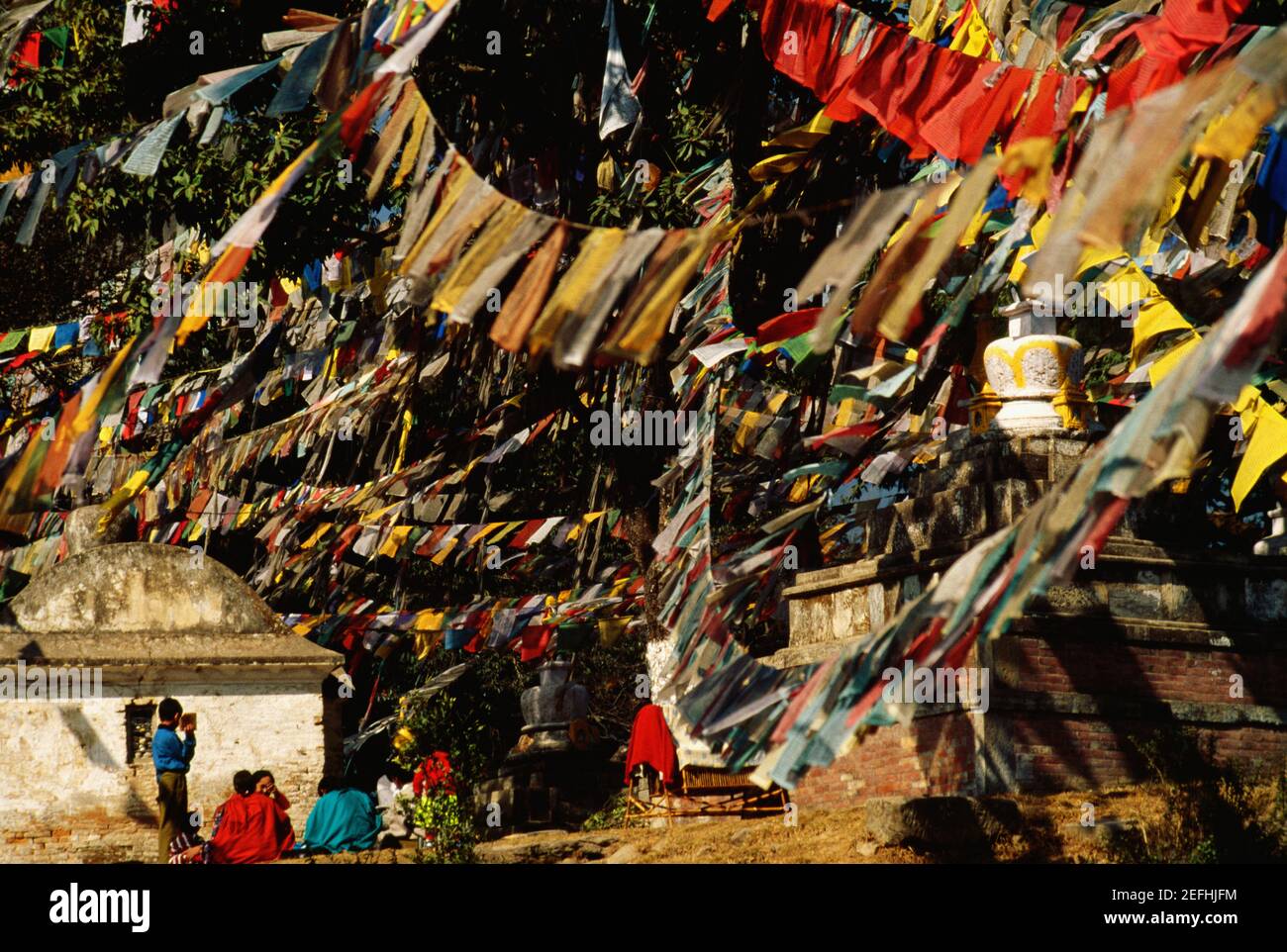 Gruppe von Menschen, die unter Gebetsfahnen sitzen, Affentempel, Katmandu, Nepal Stockfoto
