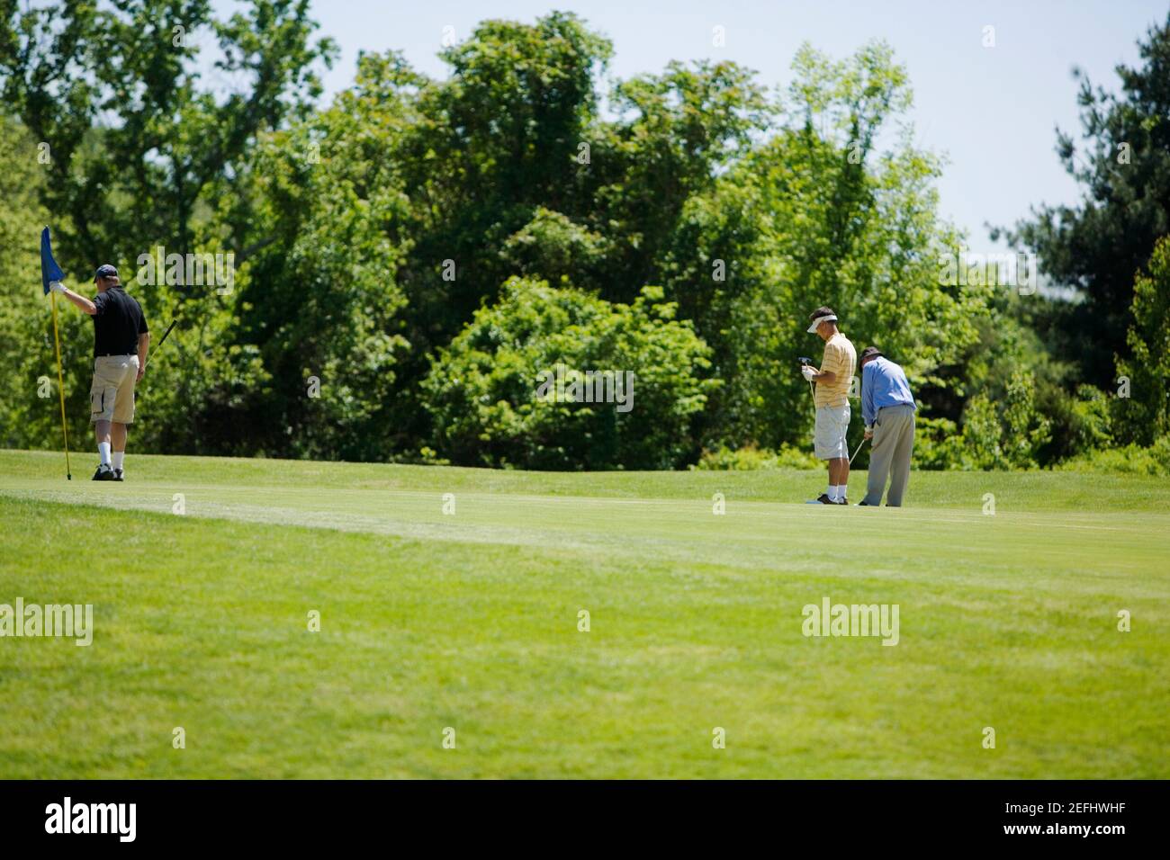 Drei Männer stehen auf einem Golfplatz Stockfoto