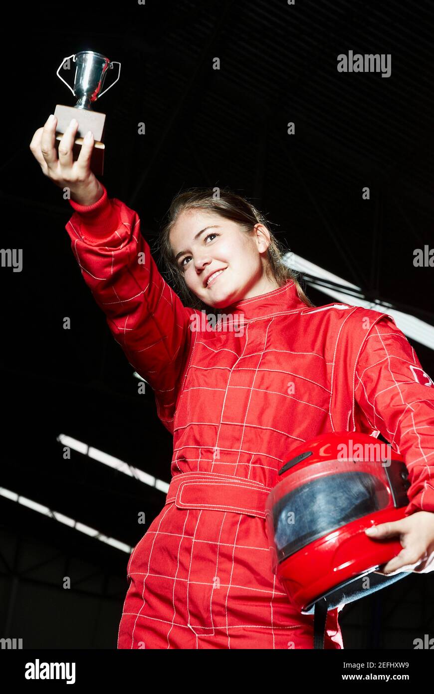 Low-Angle-Ansicht einer weiblichen go cart Racer mit einem Trophäe und Lächeln Stockfoto