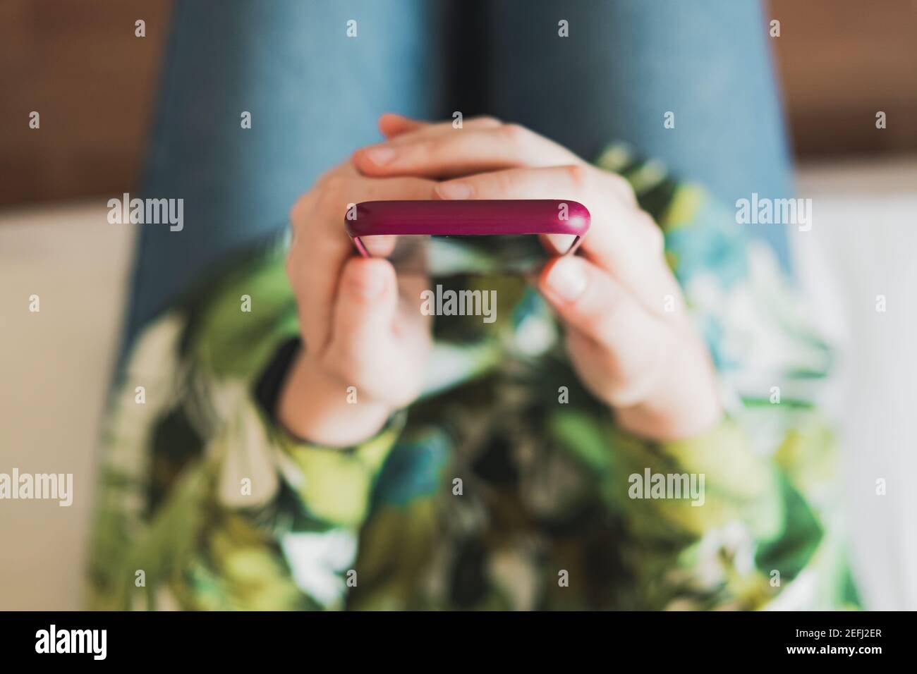 Mobiltelefon in den Händen der Frau, von oben mit dünner Schärfentiefe aufgenommen. Weibliche Person, die ein Smartphone in den Händen hält Stockfoto