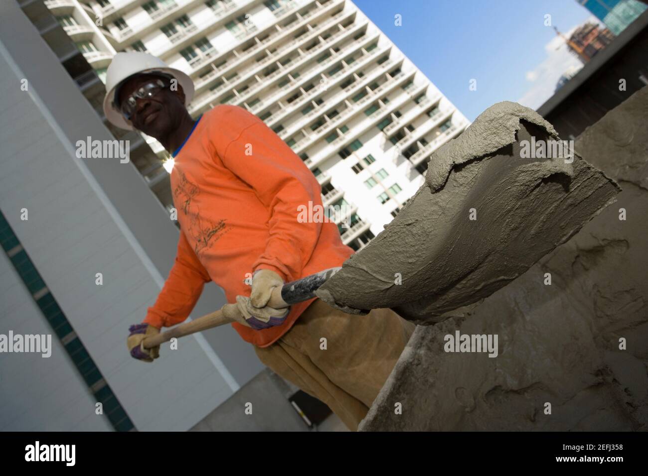 Low-Angle-Ansicht eines männlichen Bauarbeiters schaufeln Zement Stockfoto