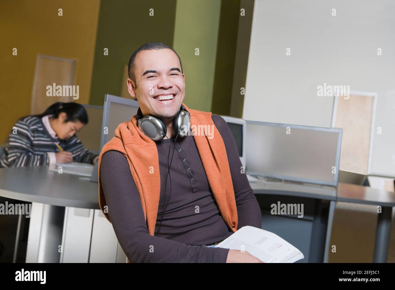 Porträt eines jungen Mannes, der in einem Computerlabor sitzt Und lachend Stockfoto