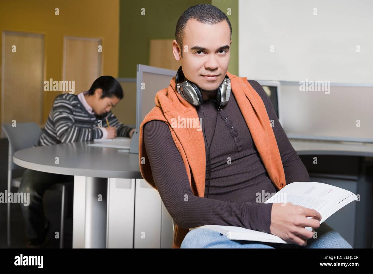 Porträt eines jungen Mannes mit einem Buch in einem Computerlabor Stockfoto