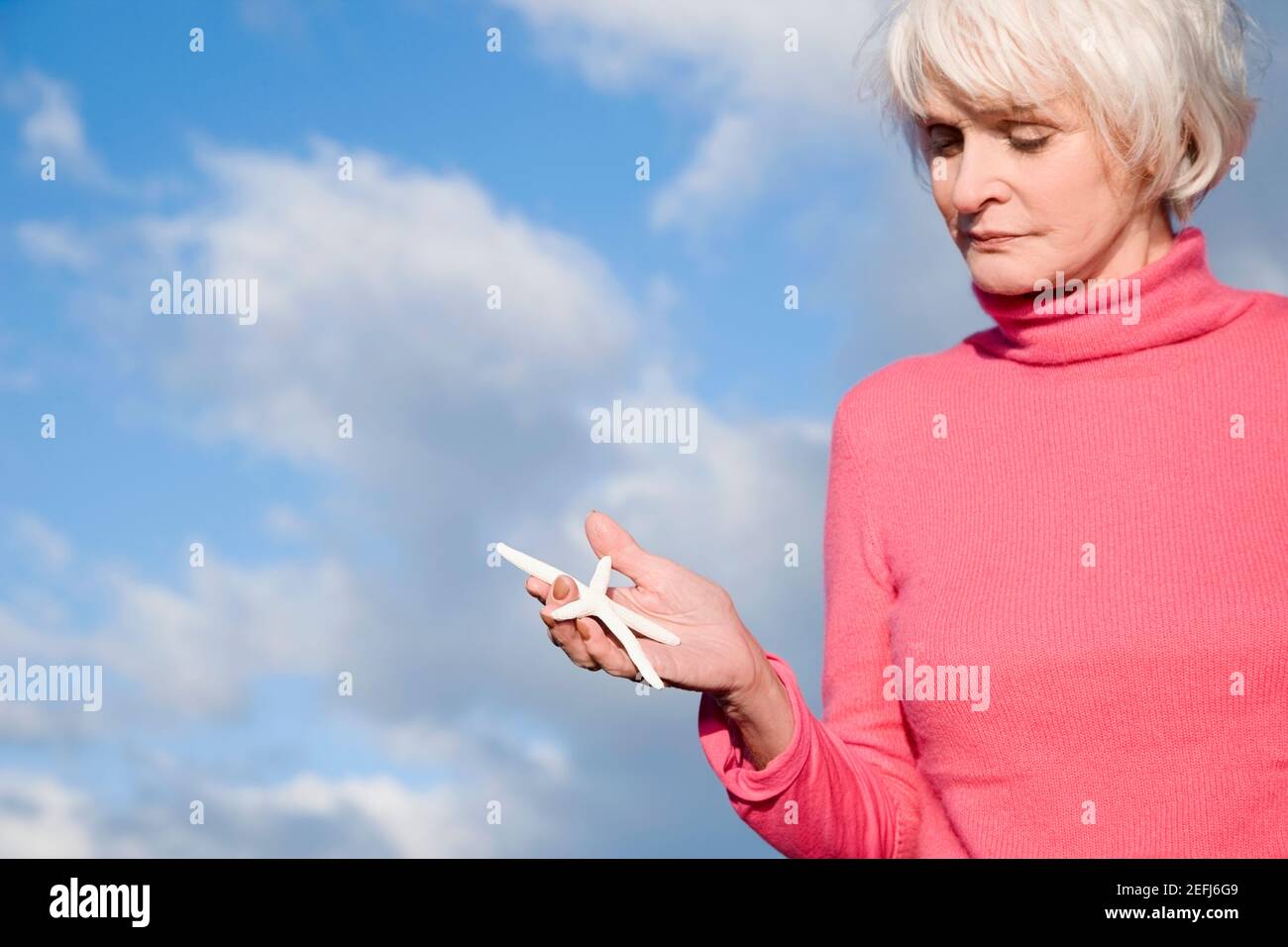 Nahaufnahme einer älteren Frau, die einen Seesterne in der Hand hält Stockfoto