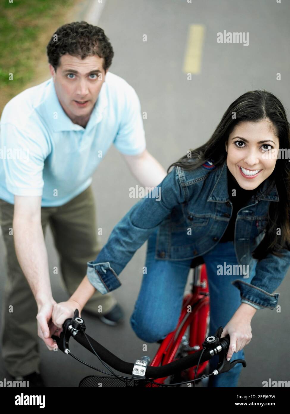 High-Angle-Ansicht eines mittleren Erwachsenen Mann hilft ein Frau mit mittlerem Erwachsenen fährt ein Fahrrad Stockfoto