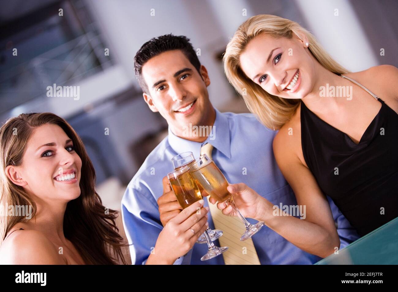 Porträt eines mittleren erwachsenen Mannes und zweier junger Frauen Toast anstoßen Stockfoto