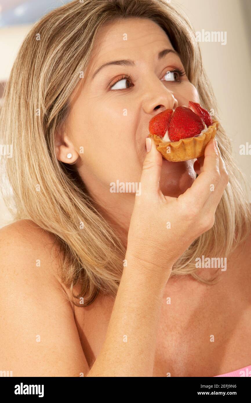 Nahaufnahme einer mittleren erwachsenen Frau, die eine Erdbeertarte isst Stockfoto