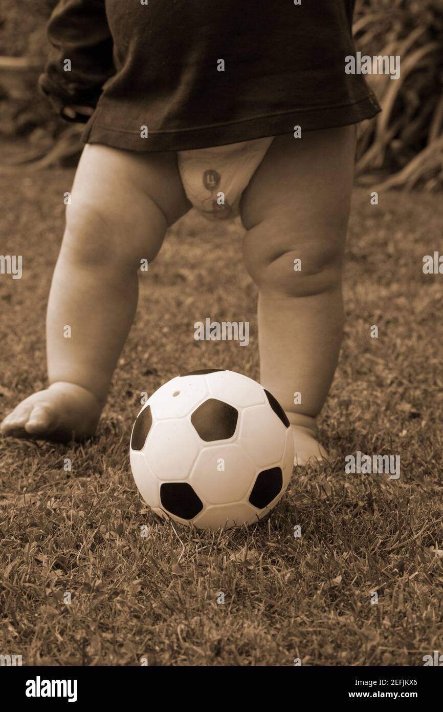 Kleines Kind spielt Fußball im Garten. Monochromes Sepia-Bild Stockfoto