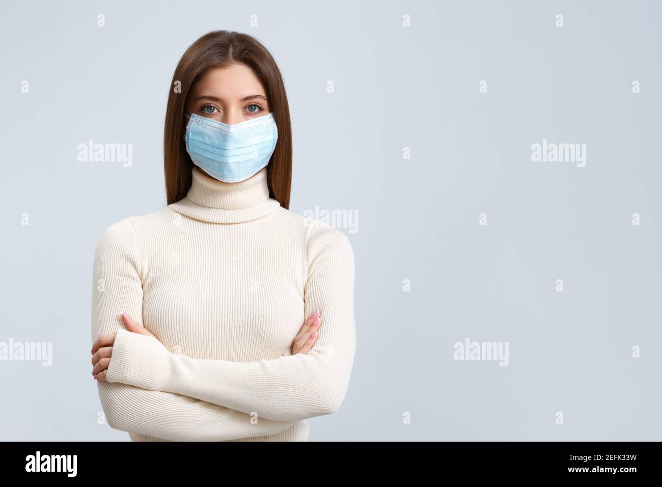 Close-up-Porträt, attraktive niedliche charmante Mädchen in schützende medizinische Maske auf pastellfarbenem Hintergrund isoliert. Stockfoto