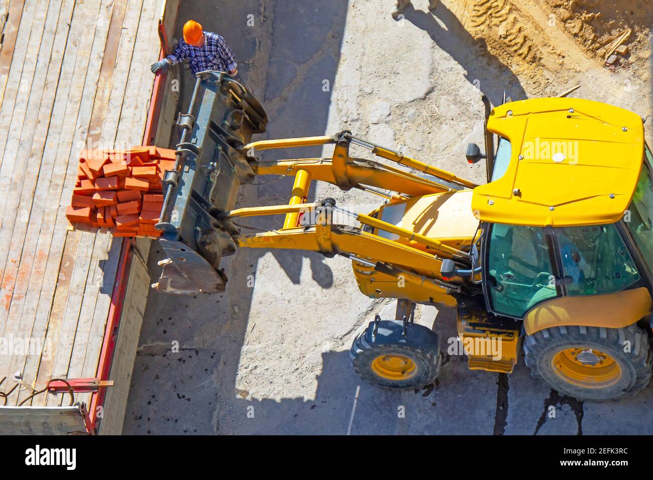 Verladen von Ziegeln in den Laderaum eines LKWs mit Ein Traktor mit Eimer Stockfoto