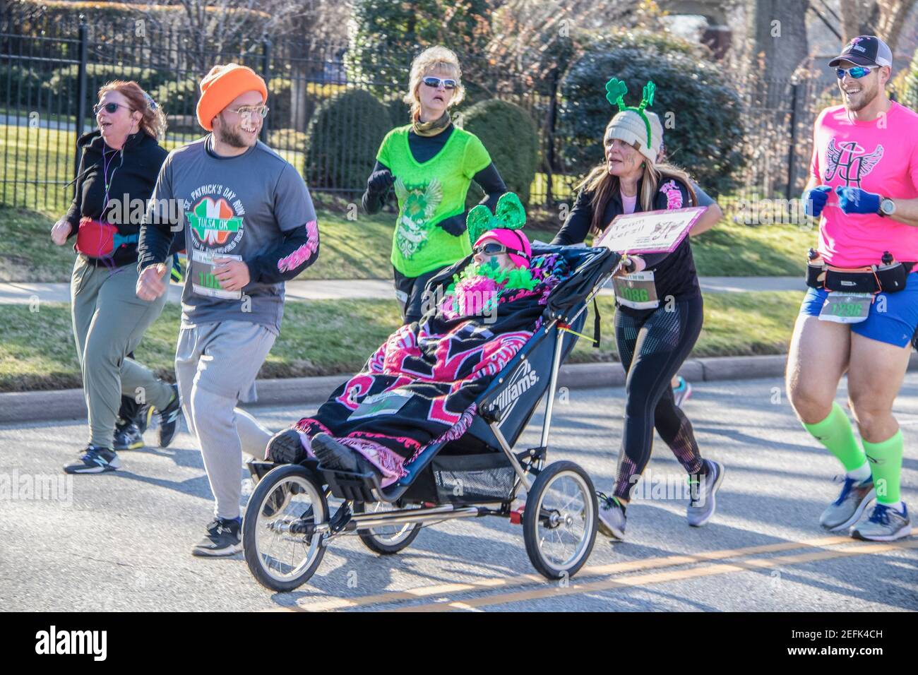 3-16-2019 Tulsa USA - Gruppe kostümierter Läufer in St. Patricks Day Parade schiebt eine behinderte Person, so dass sie kann Genießen Sie das Erlebnis: Bewegungsunschärfe Stockfoto