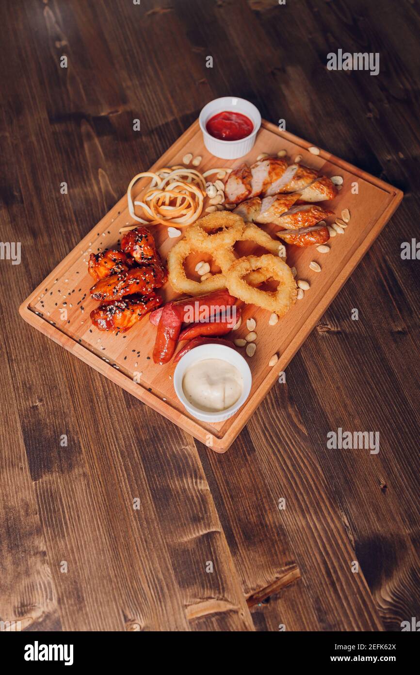 Große Auswahl an Snacks für Bier mit verschiedenen Soßen auf Pergament, Ansicht von oben Stockfoto