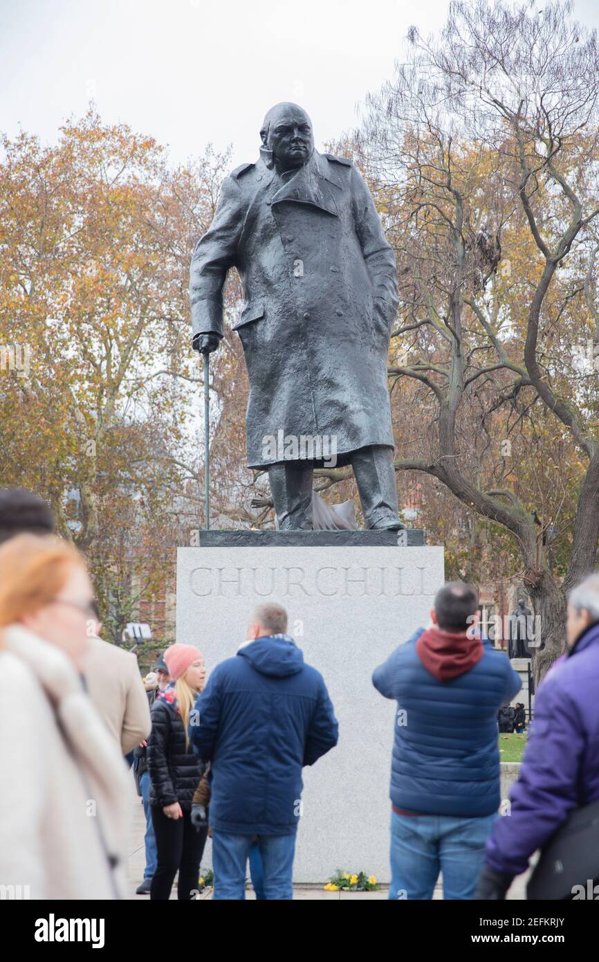 Touristen versammeln sich unter der Statue von Sir Winston Churchill im Parliament Square Garden in London, Großbritannien Stockfoto