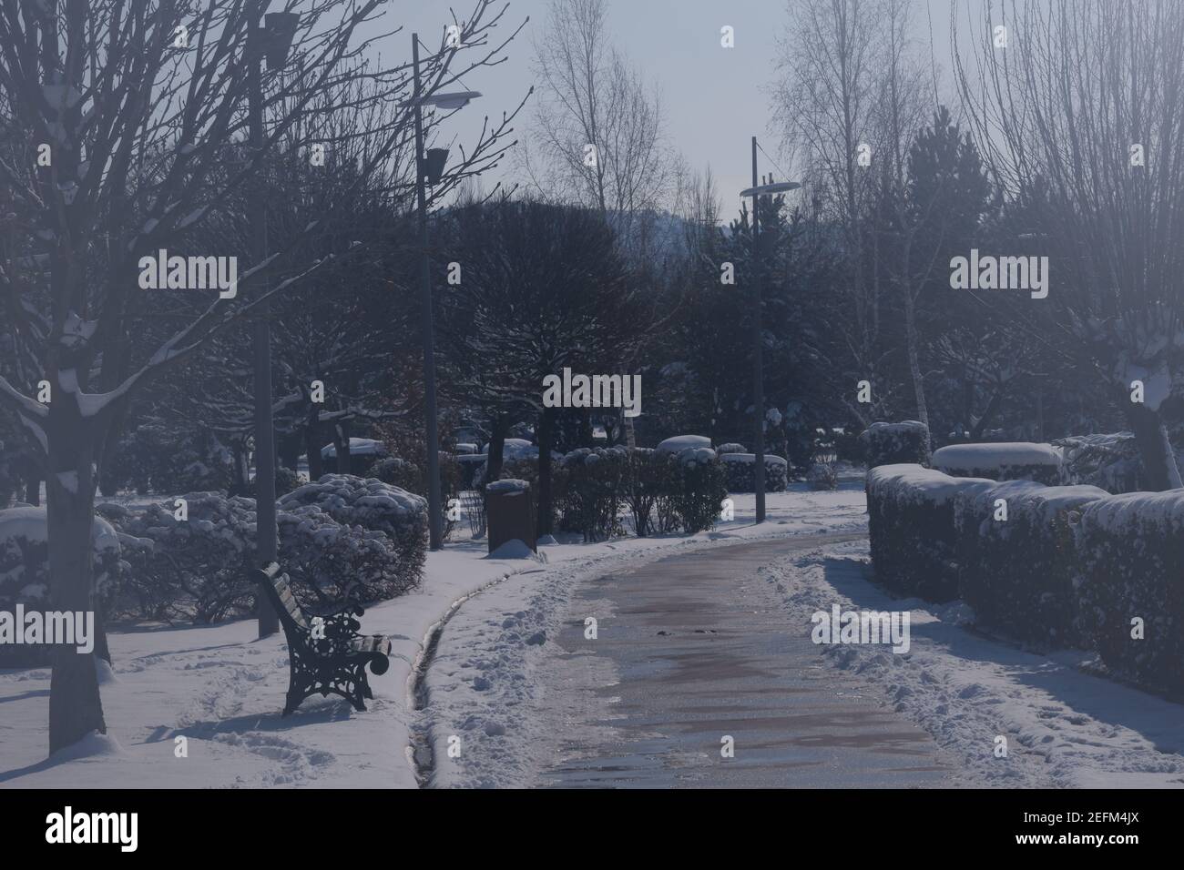 Nasse Straßen und Bänke an einem verschneiten Tag im Winter Stockfoto