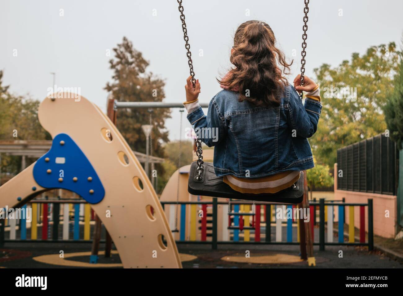 Mädchen schwingt auf einer Schaukel in einem öffentlichen Park Stockfoto