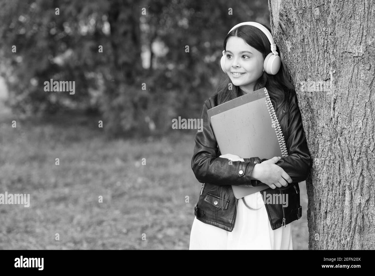 Mädchen hören Audio tragen Lehrbücher entspannende Park Hintergrund, Schulleben Konzept. Stockfoto