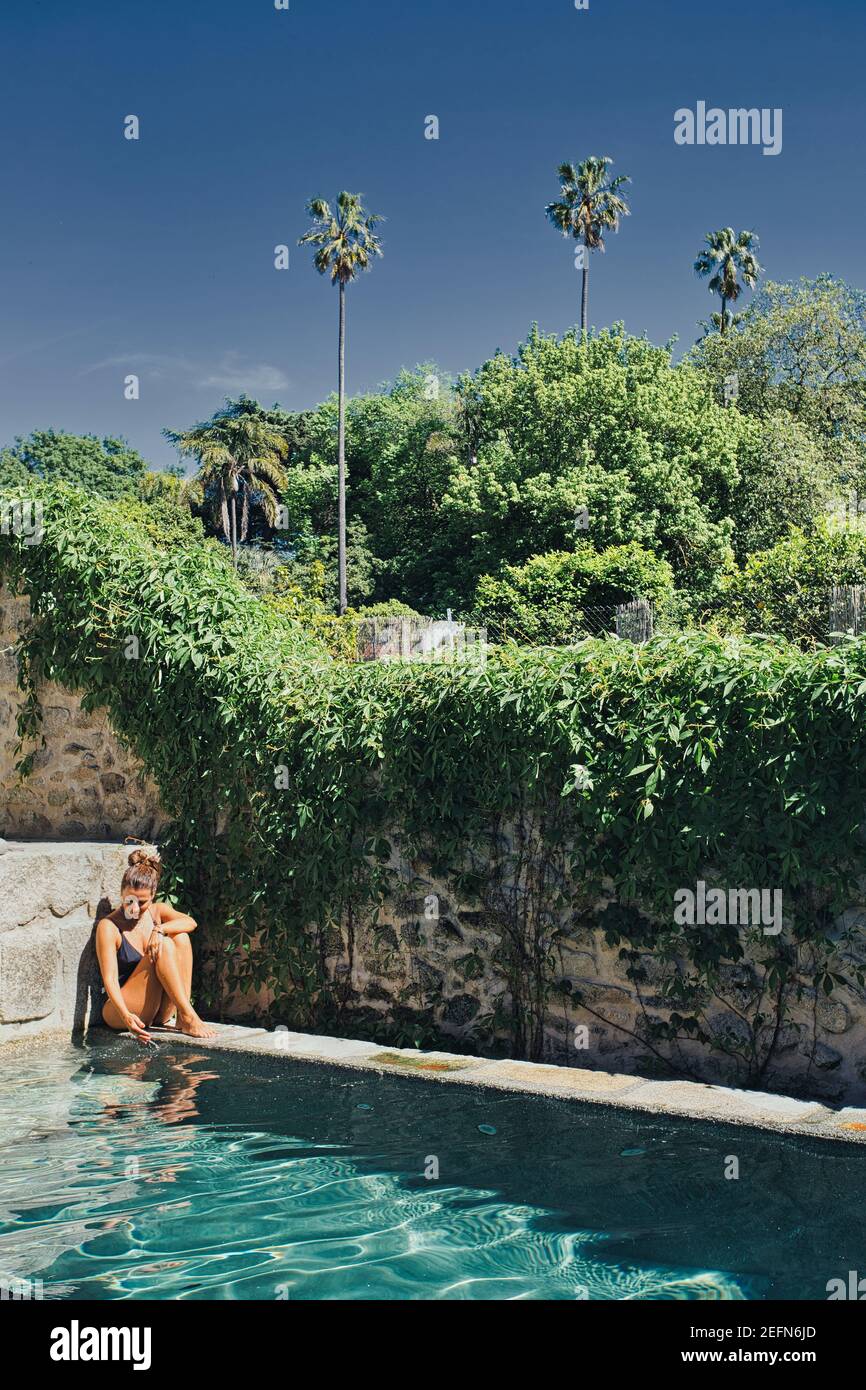 Frau, die in der Nähe des Swimmingpools im Design Hotel Tipografia do Conto in Porto, Portugal, sitzt Stockfoto