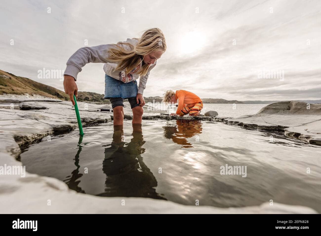 Zwei Kinder erkunden gemeinsam die Felsenpools in Neuseeland Stockfoto