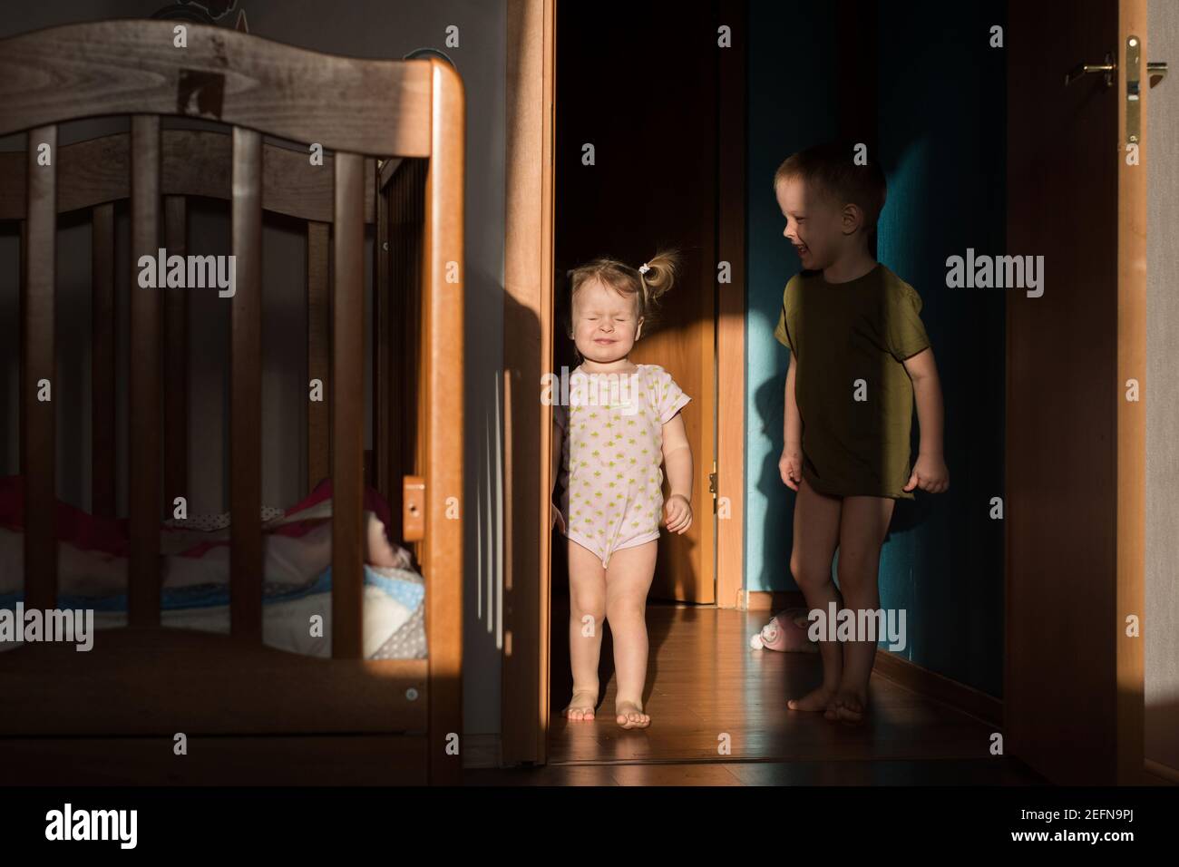 Bruder und Schwester spielen zu Hause. Das Mädchen schielt an der Sonne Stockfoto