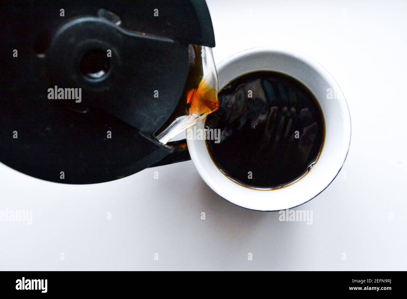 Jemand gießt heißen dunklen Kaffee in eine Tasse, die steht Auf dem Tisch Stockfoto