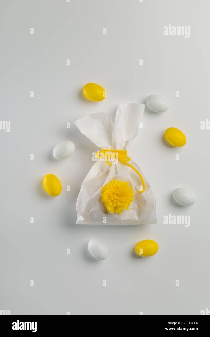 Osterkonzept - Hase geformte Tasche mit Eiern und Blumen auf hellgelbem Hintergrund, Stockfoto
