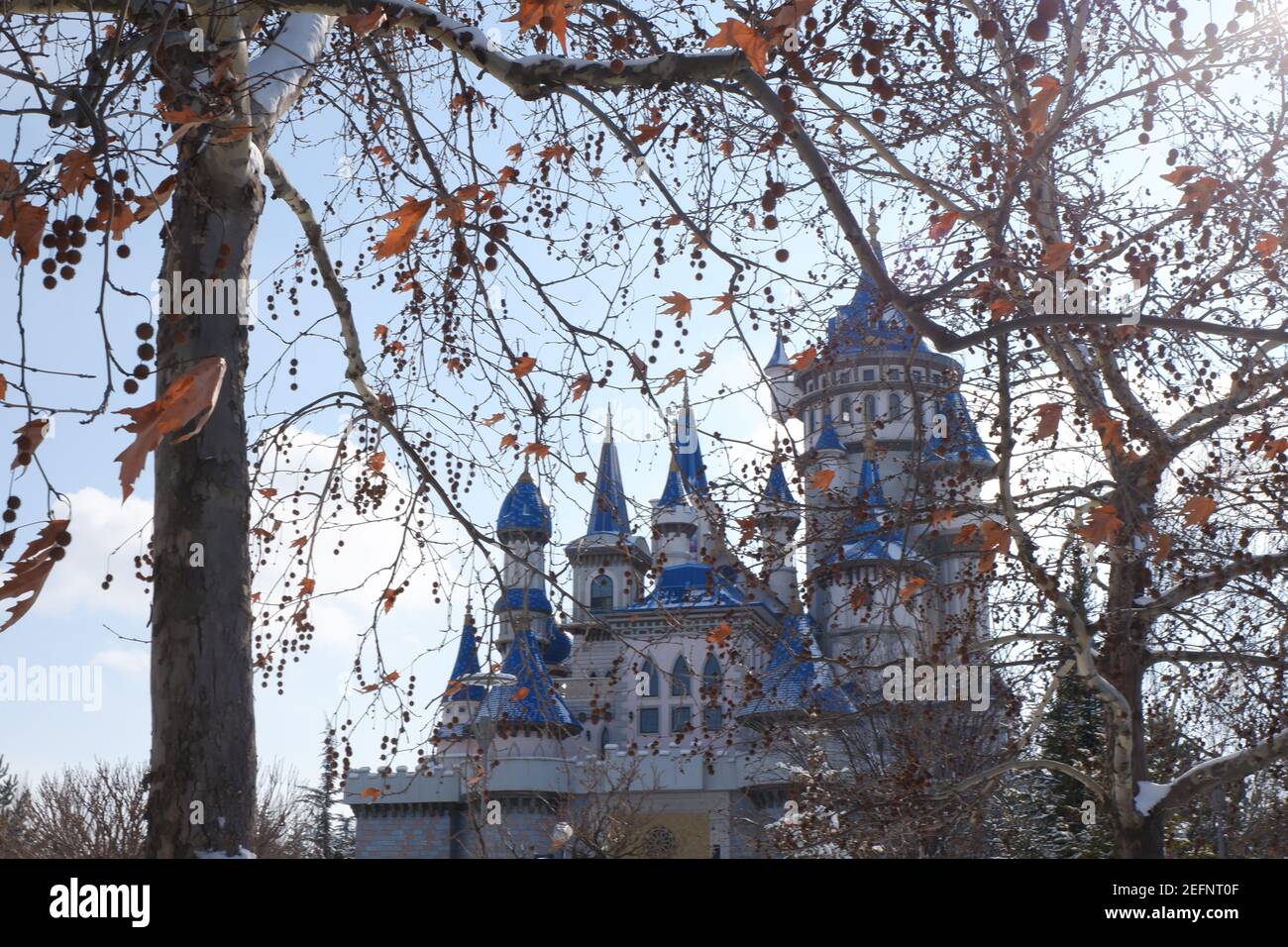 Zauberhaftes nostalgisches Blue and White Castle hinter Ästen an einem sonnigen Wintertag, während der Schnee schmilzt Stockfoto