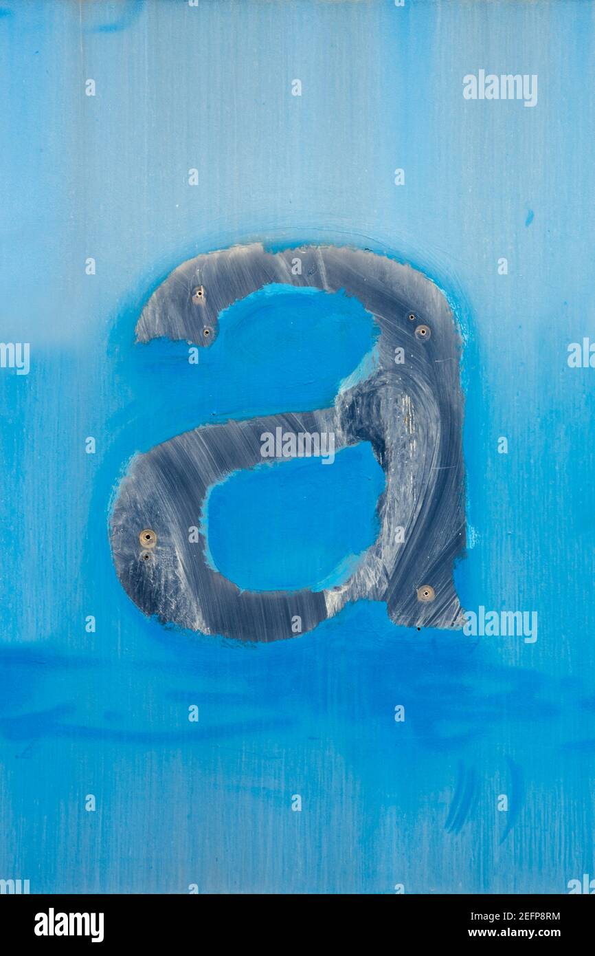 Die Spuren des verschwundenen Buchstabens a auf der ausgewaschenen blauen Oberfläche Stockfoto