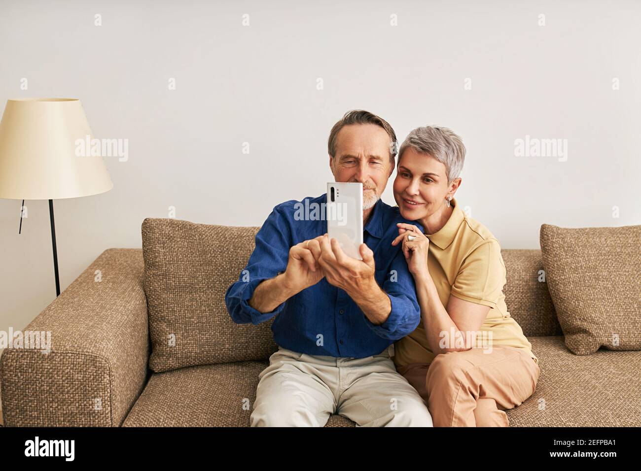 Ältere Paar in Casuals zu Hause sitzen auf der Couch Stockfoto