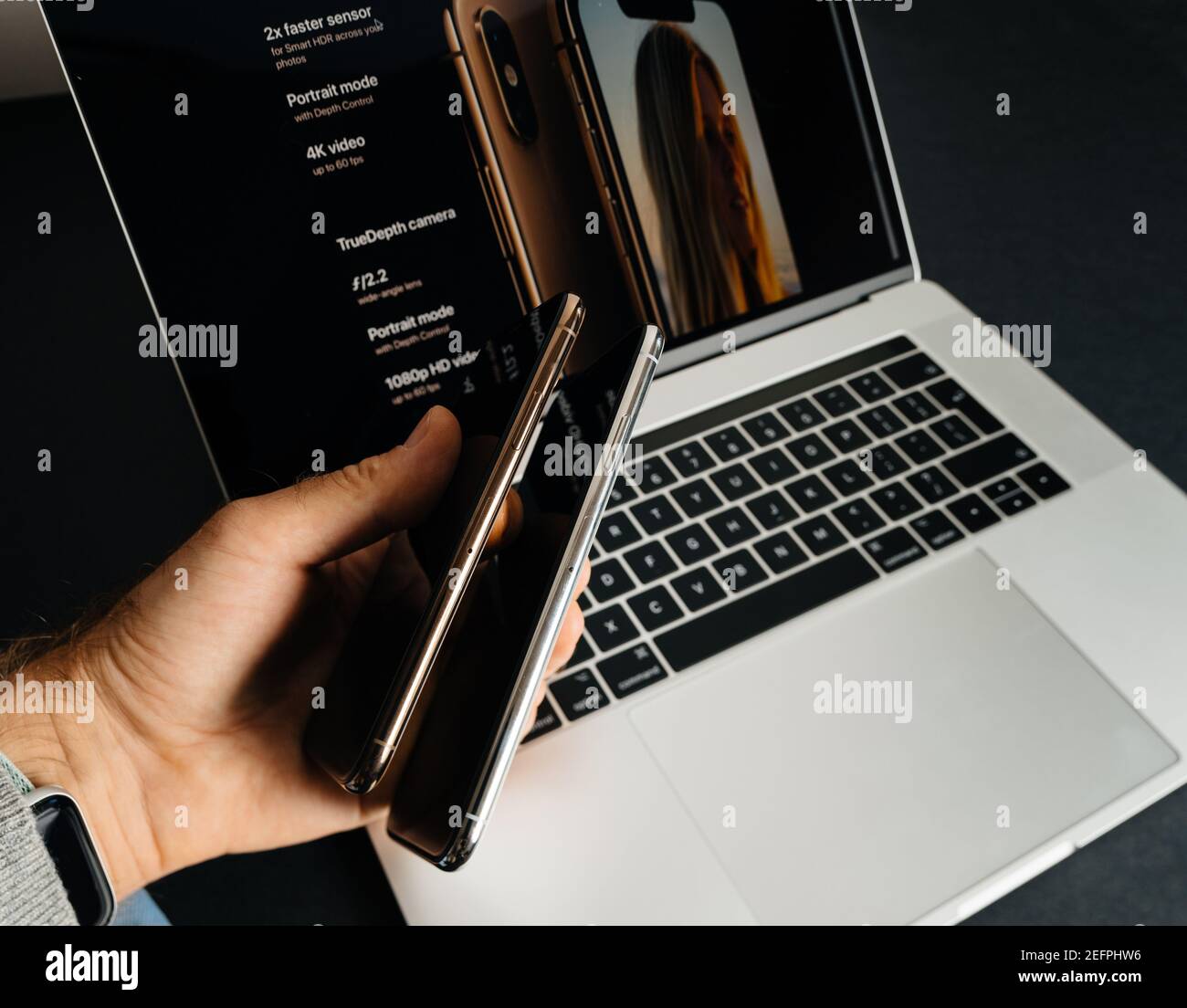 Paris, Frankreich - Sep 25, 2018: POV männliche Hand halten vergleichen, wie dünn die beiden neuen neuesten Smartphones von Apple Computers iPhone 11 12 14 Pro gegen die Pro max Versionen - mit MacBook Pro Laptop im Hintergrund Stockfoto