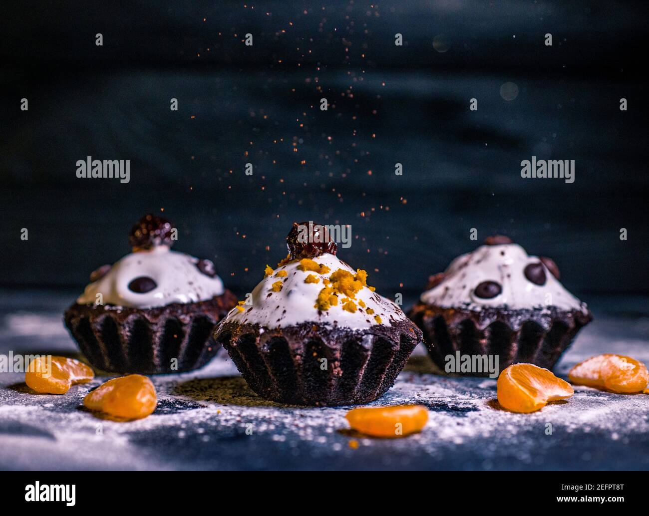 Schokoladen-Muffins bestreut mit Leckereien mit Kirschen und Schokolade und Kakao Stockfoto