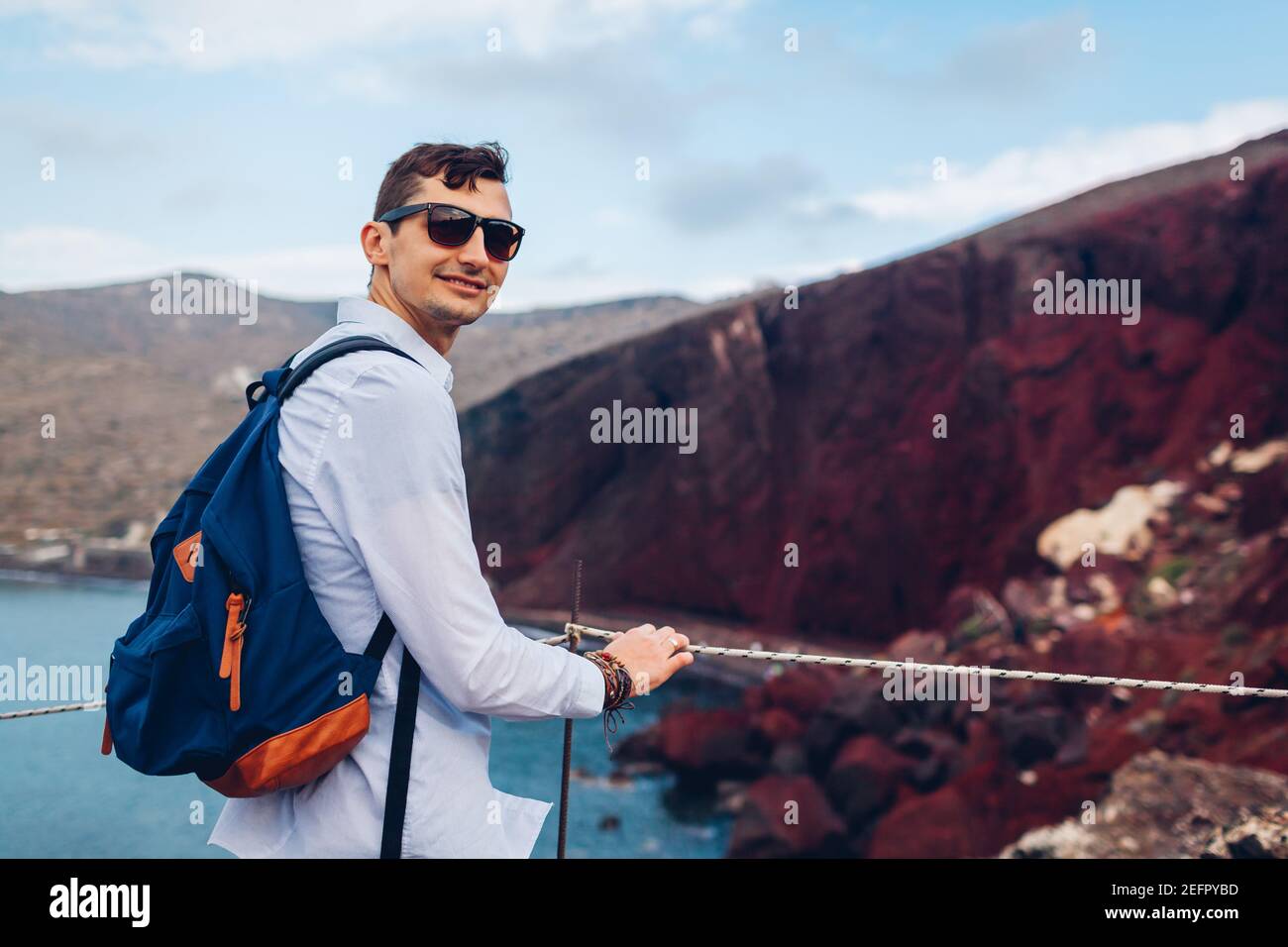 Touristen genießen Red Beach, Ägäis Meer und Berglandschaft aus Sicht Punkt in Akrotiri, Santorini Insel, Griechenland. Glücklicher Mann Rucksacktourist unterwegs Stockfoto