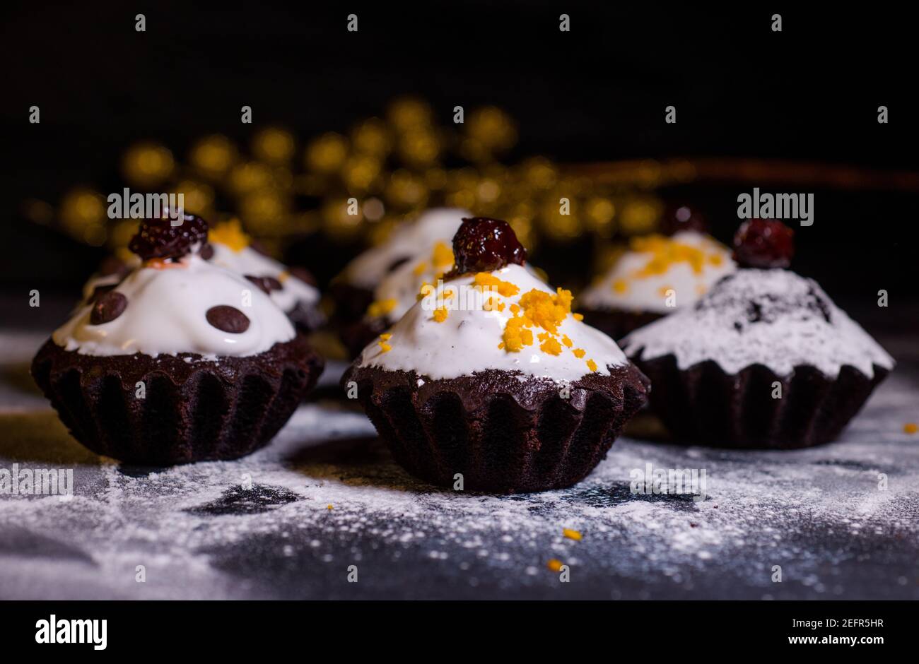 Schokoladen-Muffins bestreut mit Leckereien mit Kirschen und Schokolade und Kakao Stockfoto