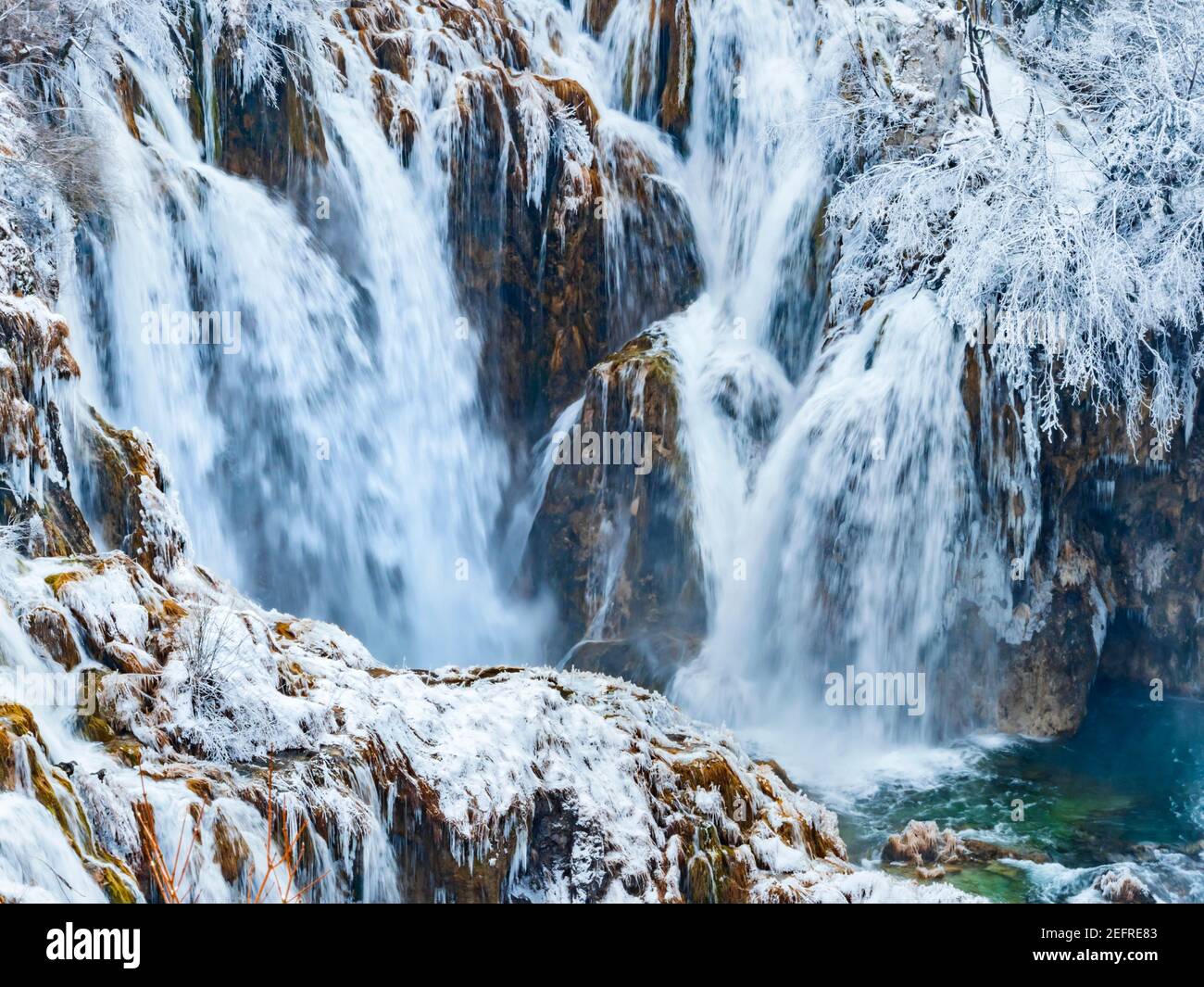 Dynamische Wintersaison Wasserfälle in Plitvicer Seen Kroatien Europa mit Schnee Eis Wasserfluss fließt auf felsigen unwegsamen Gelände Streuseln Wasser Stockfoto