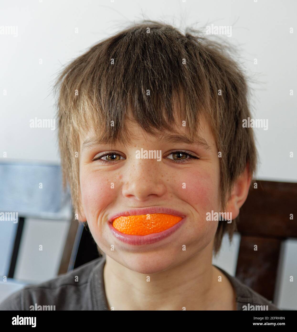 Ein kleiner Junge (8 Jahre) Mit einem Lächeln auf der Orangenschale Stockfoto