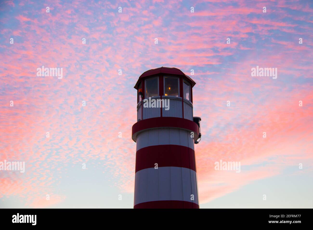 Leuchtturmspitze in rot-weißer Farbe aus tiefem Winkel auf farbenprächtiger Sonnenuntergangshimmel-Hintergrund, Podersdorf am See Leuchtturm, Österreich, Neusiedler See Stockfoto