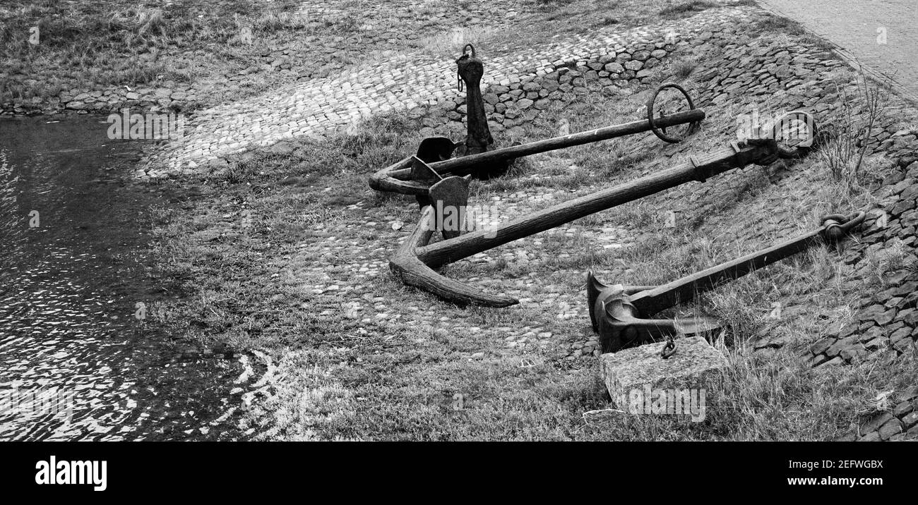 Graustufenaufnahme alter rostiger Anker auf dem Boden Stockfoto